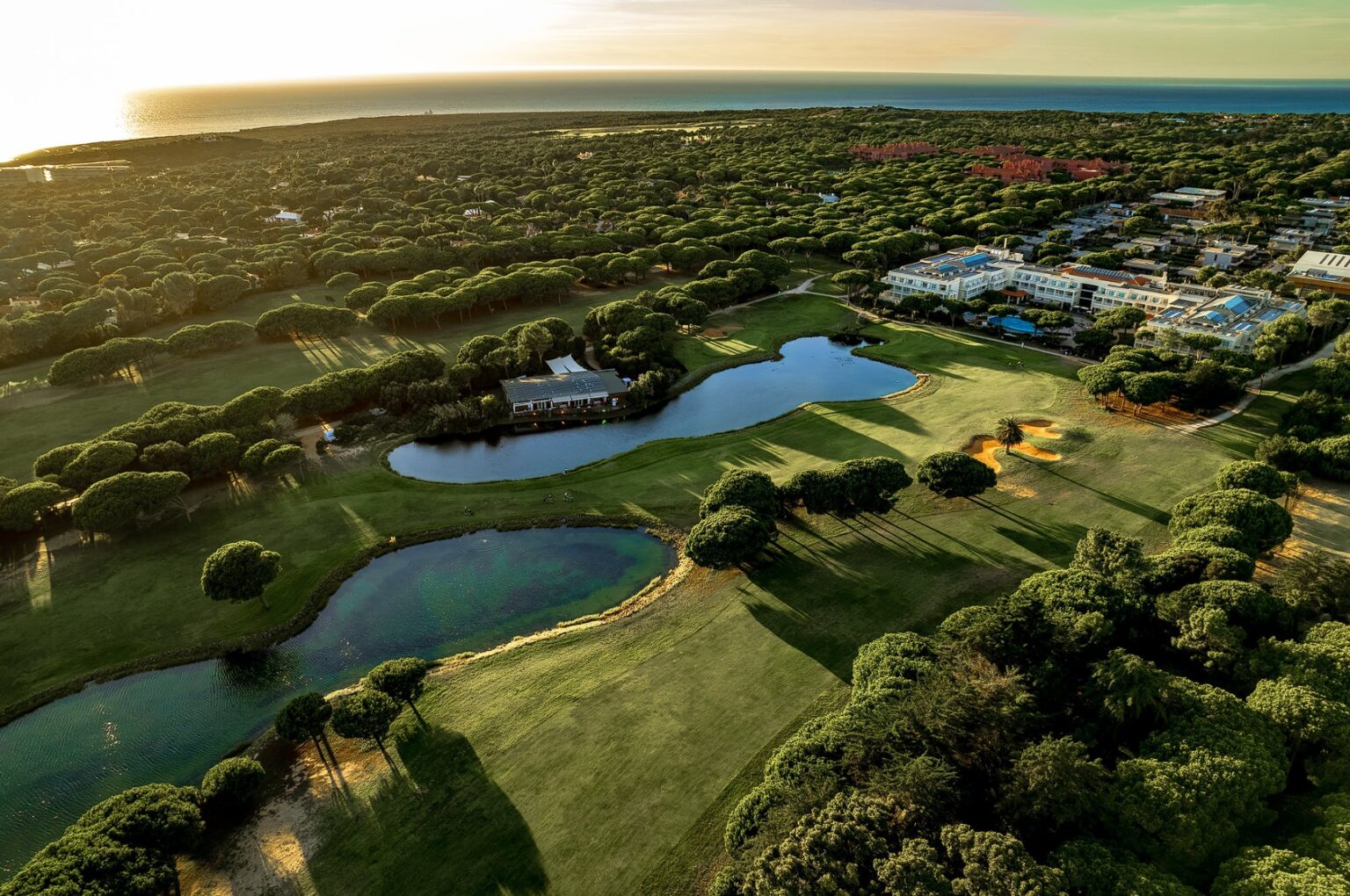 Flygfoto över Quinta da Marinha Golf i Cascais med golfbanan i förgrunden och Atlanten i bakgrunden längs Portugals kust.